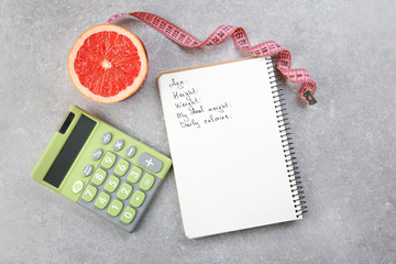 Diet concept. Measuring tape, grapefruit, calculator and notebook on gray background