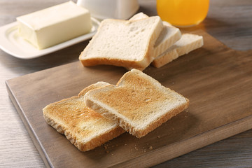Wooden board with tasty breakfast toasts on table