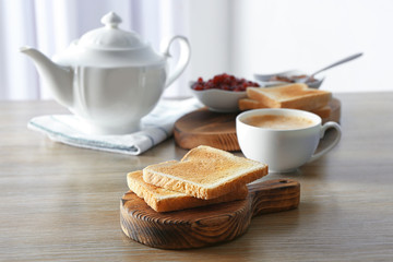 Wooden board with tasty breakfast toasts on table