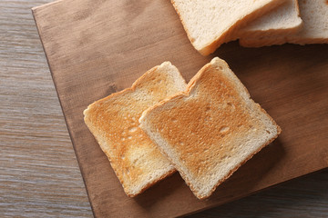 Wooden board with tasty breakfast toasts on table