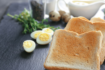 Slate plate with tasty breakfast toasts on table