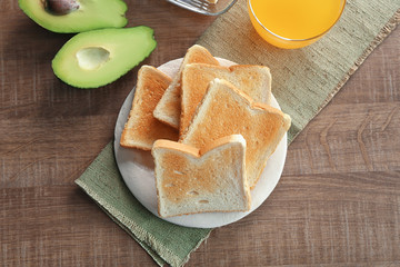 Plate with tasty breakfast toasts on wooden table