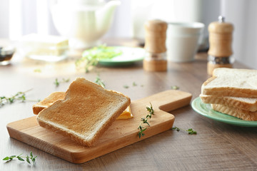 Wooden board with tasty breakfast toasts on table