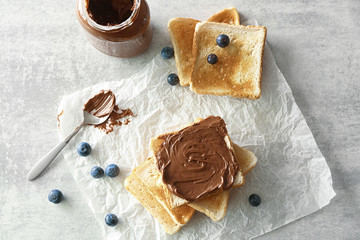 Tasty breakfast toasts with chocolate paste on table