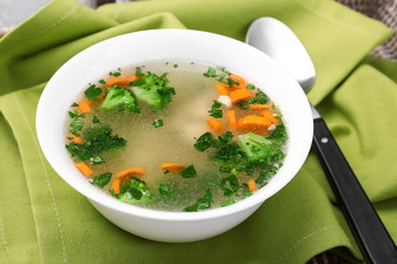 Plate with homemade chicken soup on wicker tray