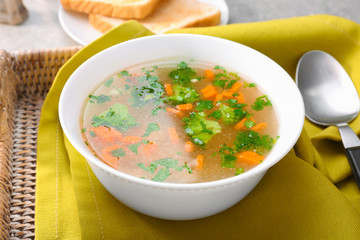 Plate with homemade chicken soup on wicker tray