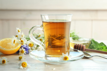 Glass cup with delicious chamomile tea on table