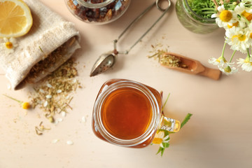Mason jar with tasty chamomile tea on light wooden table