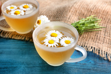 Obraz na płótnie Canvas Herbal tea with chamomile flowers in glass cups on color wooden background