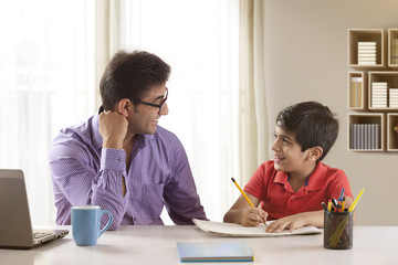 Father helping son with homework at desk