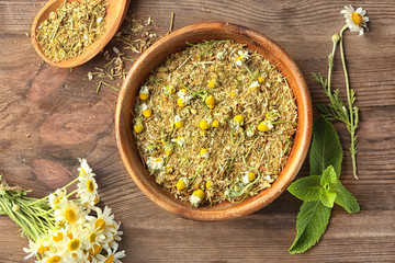 Bowl with dried and milled chamomile flowers on wooden background