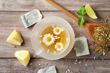 Glass cup with tasty chamomile tea on wooden background