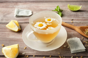 Glass cup with tasty chamomile tea on wooden background