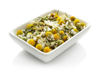 Bowl with dried chamomile flowers on white background