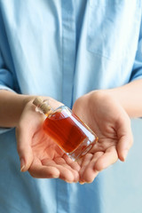 Woman holding aromatic vanilla extract in bottle, close up