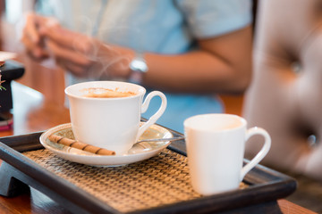 A cup of  coffee  on the wooden  table with woman background.