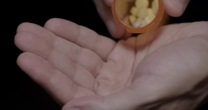 Pouring Opiates Into Hand Slow Motion Close Up. a close up of someone pouring a bunch of prescription opiate pills into their hand in slow motion
