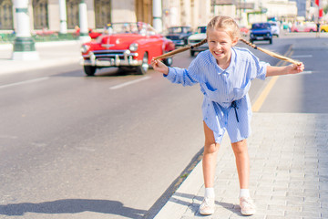 Adorable little girl in popular area in Old Havana, Cuba. Portrait of kid background vintage classic american car