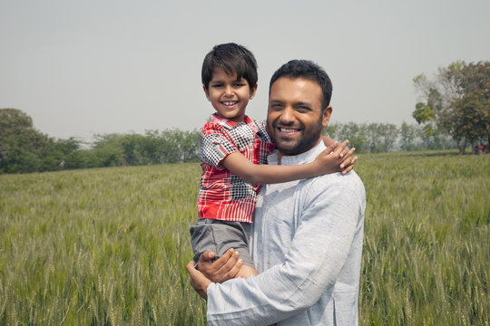 Portrait of a happy man carrying his son with wheat field in background 