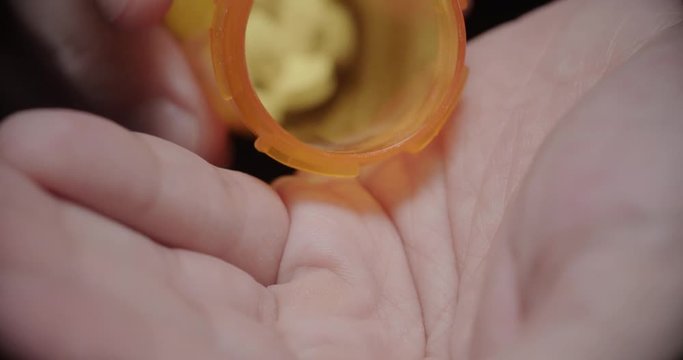 Pouring Opiates Into Hand Slow Motion Extreme Close Up. a close up of someone pouring a bunch of prescription opiate pills into their hand in slow motion
