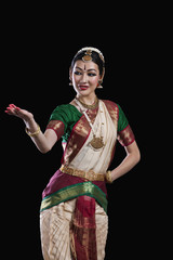Female Bharat Natyam dancer performing over black background