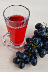 A glass of juice and black grapes
