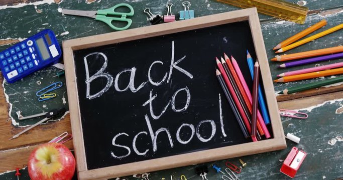 Text written on slate with school supplies