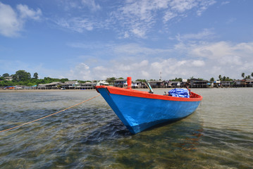 Naklejka premium Small fishing boat and the village on seaside