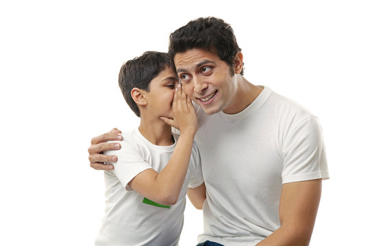 Boy whispering in his fathers ear 