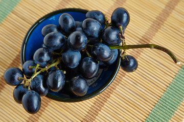 A bunch of black grapes in a blue cup