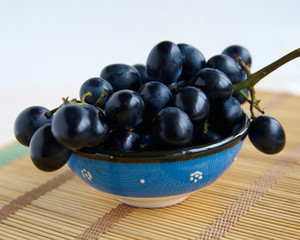 A bunch of black grapes in a blue cup