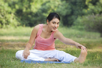 Portrait of woman on grass stretching 