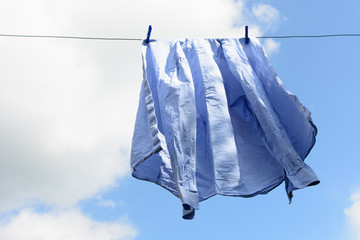 Men's blue shirt dries on the clothesline