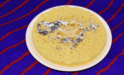 Indian disc-shaped mithai, ghevar sweet garnished with dry fruits and silver leaf.