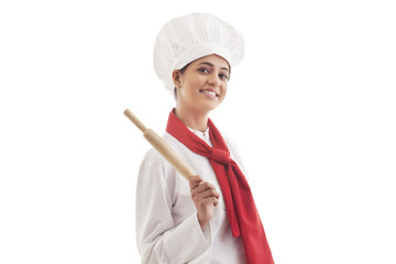 Portrait of young female chef holding rolling pin isolated over white background 