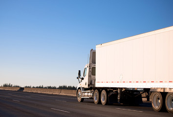 Day cab semi truck with long trailer running on roadway
