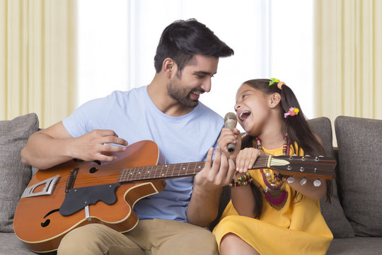 Father playing guitar and daughter singing