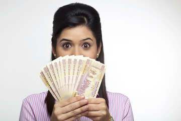 Female executive hiding her face with currency 