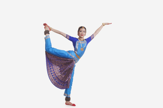 Full length of young woman performing Bharat Natyam dance over white background