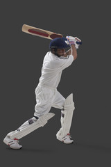 Young male player playing cricket isolated over gray background 