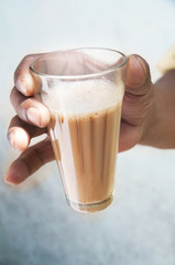 Close-up of man's hand holding glass of chai 