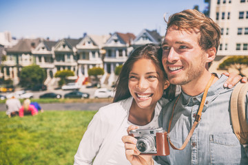 San Francisco Painted Ladies houses tourist couple on USA travel vacation taking photography...