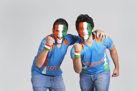 Exhilarated male cricket supporters with a painted face in tricolor cheering over colored background 