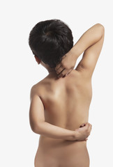 Naked boy scratching his back 