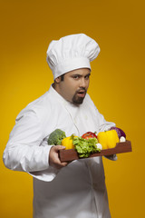 Portrait of chef with tray of vegetables