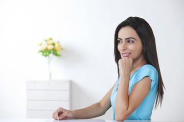 Beautiful young woman looking away at home