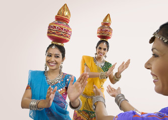 Gujarati women dancing with a kalash on their head  - obrazy, fototapety, plakaty