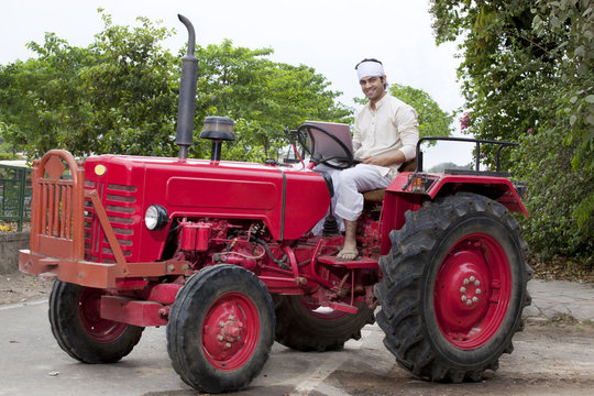 Portrait of a farmer with a laptop sitting on a tractor