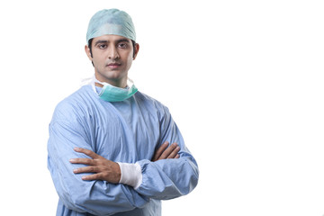 Portrait of male surgeon with hands folded over white background 