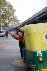 Man waving from an auto rickshaw 